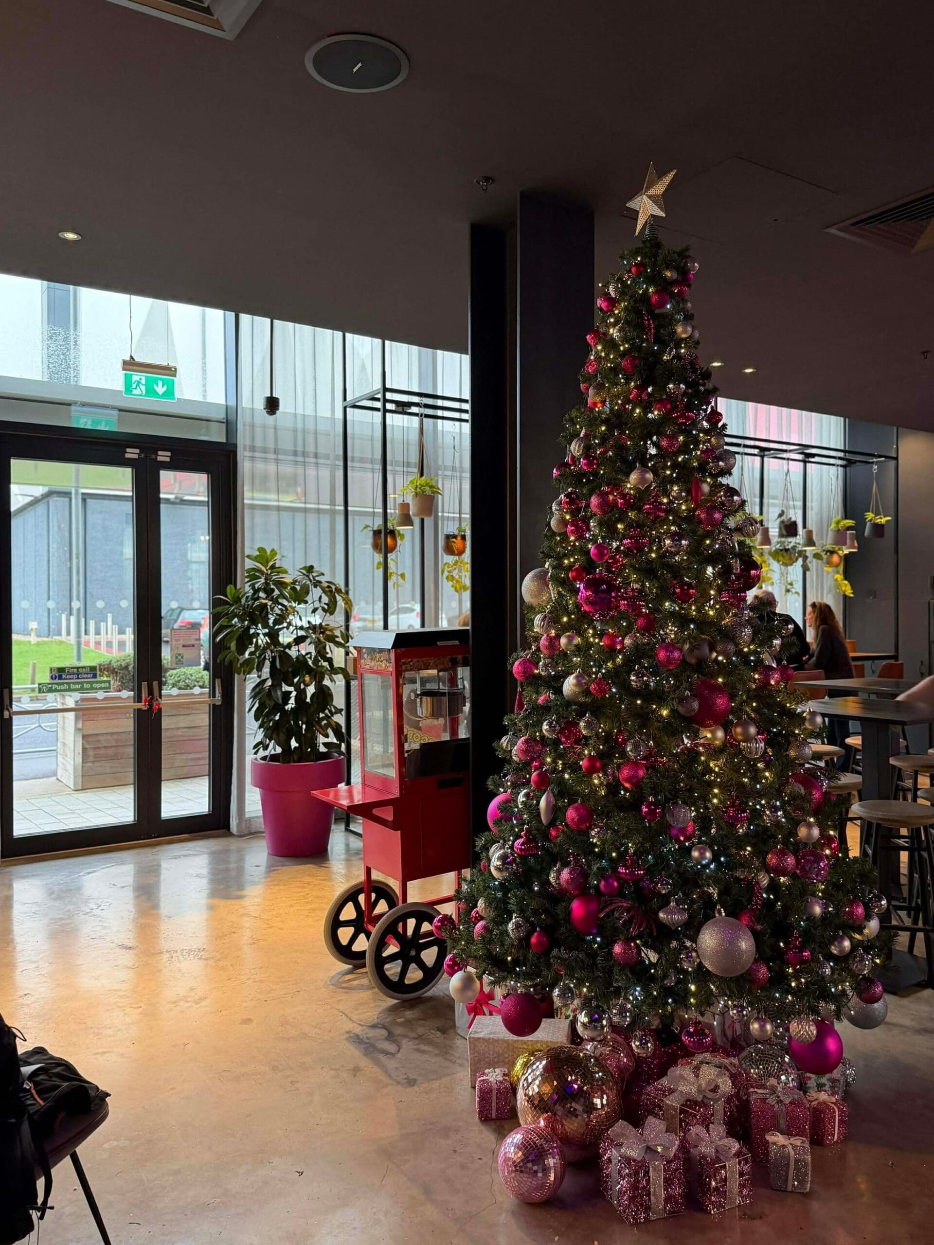 Pink and silver Christmas tree in a glass-fronted lobby, West Midlands