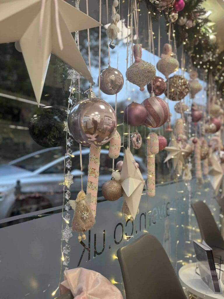 Christmas shop window display with hanging baubles and stars, Worcestershire